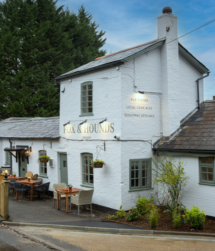 The exterior facade, signage, and seating area of The Fox & Hounds in Bursledon, with flower baskets hanging on the wall.