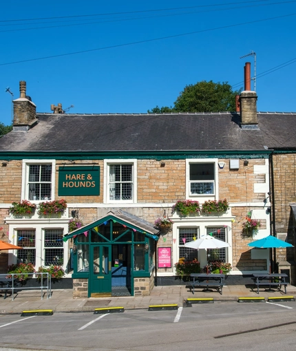 The exterior facade and beer garden seating area at The Hare & Hounds.
