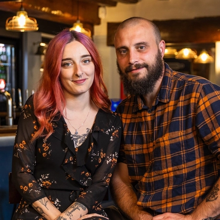 Two people sitting in the restaurant of a pub.