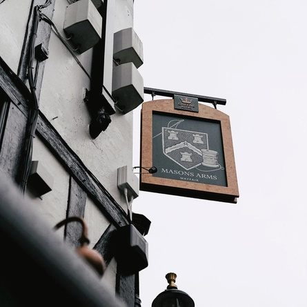 A view looking up from the ground of the pub sign on the exterior wall of the Masons Arms.