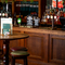 A close up view of a circular, wooden restaurant table with four bar stools, standing in front of the wood panelled bar inside The Junction.