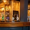 The wood panelled bar inside The Tamar in Crownhill, with glasses hanging in racks above the counter, and bottles of alcoholic spirits on wooden shelves behind the bar.