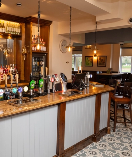 A close up view of the bar inside The Hussey Arms in Brownhills, with bottles of wine and alcoholic spirits on wooden shelves behind the counter.