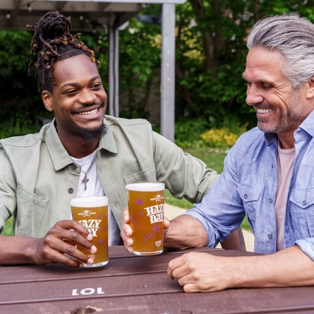 Two people sat in a beer garden enjoying a pint of Hazy Day.