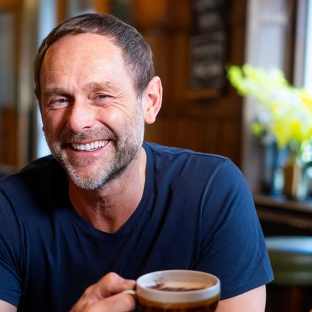 An image focusing on a person sat with a group of people at a table within the restaurant area with a breakfast dishes and drinks available at Urban Social venues.