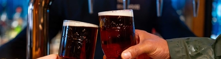 Two hands holding a pint of beer.