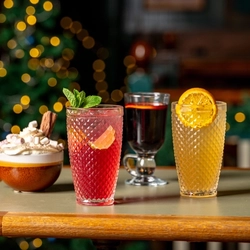 Three glasses of Christmas drinks and a mug of hot chocolate, sitting on a wooden table.
