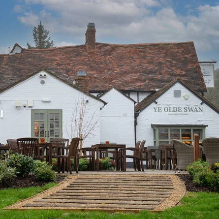 The exterior facade, signage, and beer garden seating area of Ye Olde Swan.