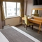 A interior family hotel bedroom with a double bed, two single beds, a dressing table with mirror and a TV at The Commodore.