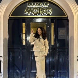 A woman stood in teh doorway of a pub.