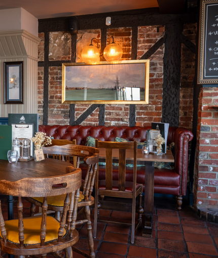 The interior restaurant seating area with tables, chairs, tiled flooring and brickwork walls with wooden beams at The Spice Island.