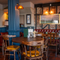 The interior restaurant seating area with tables, chairs, tiled flooring and brickwork walls with wooden beams at The Spice Island.