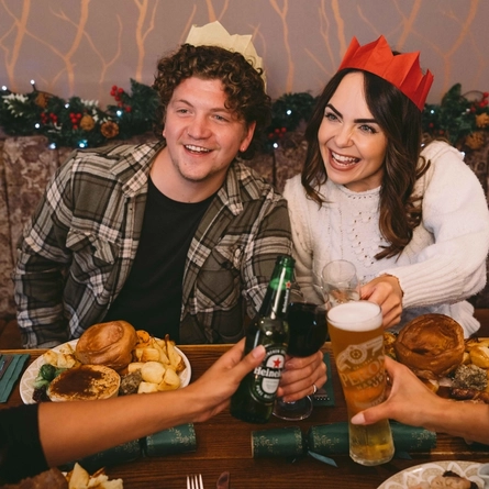A group of people seated at a festive decorated table  with plated meals and drinks in front of them.