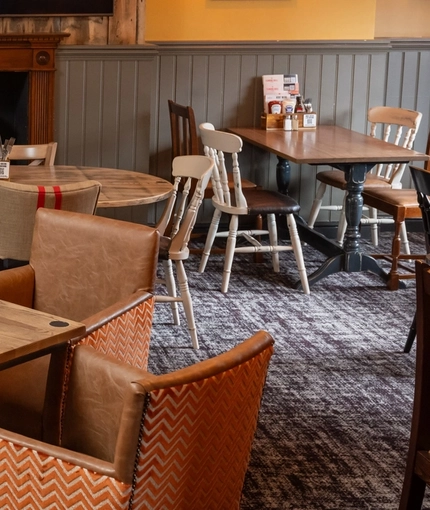 The interior restaurant seating area at The Tamar in Crownhill, with an upholstered booth seat, a fireplace, and a TV on the wall above it.