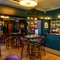 The bar and interior restaurant seating area at The Globe; with checkerboard tiles in front of the counter, TVs on the walls, and bar stool seating.