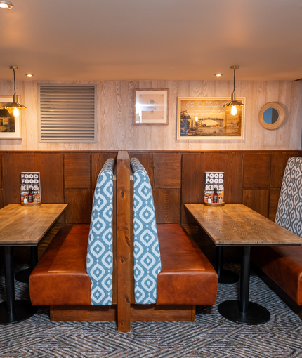 An interior restaurant seating area at The Wrekin Giant, with upholstered booth seats, and framed artwork on the wall.
