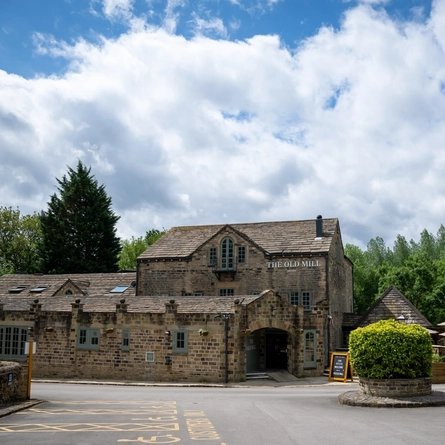 The exterior facade and beer garden seating area of The Old Mill in Brighouse.