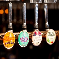 A close up view of the beer taps for Hazy Day, Level Head, Old Mout Berries & Cherries, and Inch's; on the bar at The Talbot.