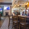 Interior bar of a pub with a seating area, a TV, a gambling machine and a fireplace.