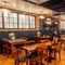 The interior restaurant seating area of the Monument, with wooden tables and chairs, booth seating, and TVs on the walls.