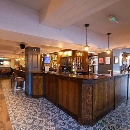 The bar of The Cumberland, with seating at the bar and some restaurant tables.