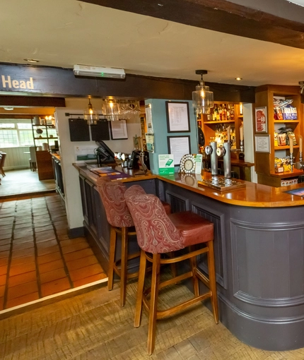 The bar area of The Old Bell with some stools around it.