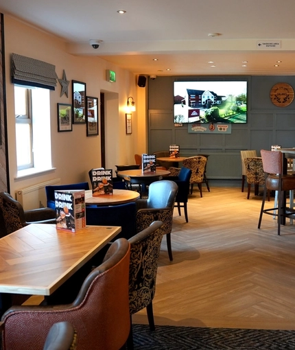 The interior restaurant seating area at The Steam Turbine in Rugby, with a TV on the wall, and a dartboard.