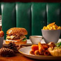 A plated burger on a festive decorated table with a pint of beer.