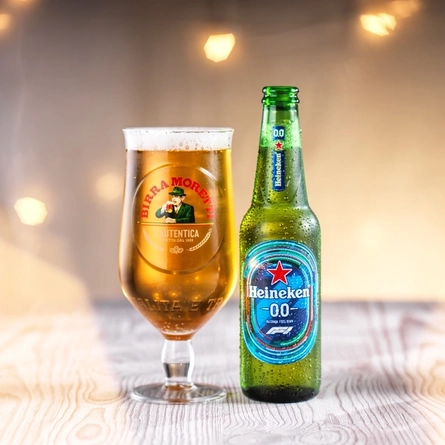a bottle of Heineken beer next to a pint of Moretti beer