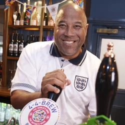 John Barnes behind the bar at The Endbutt in Liverpool, wearing an England football shirt and pulling a pint of 4-4-Brew Pale Ale.