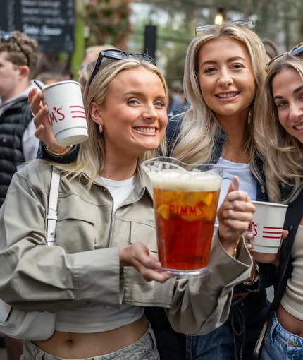 An image of 3 friends stood within the beer garden area with drinks during The Boat Race event at The Crabtree.