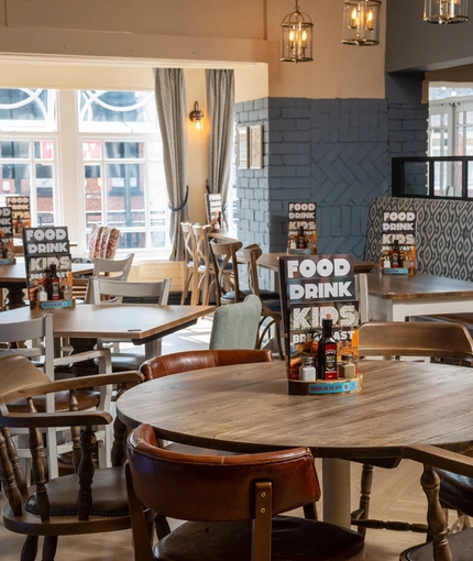 An interior restaurant seating area at The Cherry Tree; with upholstered booth seating, and large windows.