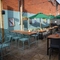 The paved, exterior beer garden seating area at The Grosvenor in Felixstowe, with shade umbrellas on some of the tables, and string lights overhead.