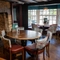 The interior restaurant seating area at The Ship in Bedford; with a large stone fireplace, upholstered bench seats in the large bay window, and wooden beams on the ceiling.
