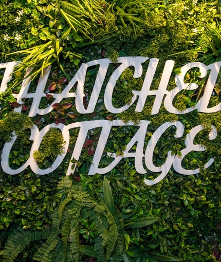 A sign on a grassy wall which reads 'Thatched Cottage'.