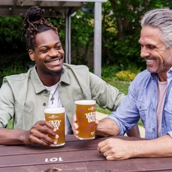 Two people sat in a beer garden enjoying a pint of Hazy Day.
