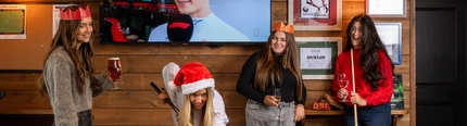 An interior shot of people celebrating Christmas in the sport/pub games area at a Flaming Grill venue.