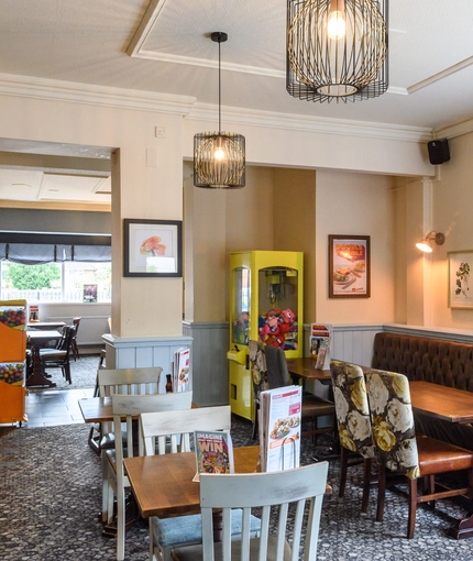 Interior dining area of a pub with a bar, a candy machine and a claw machine.