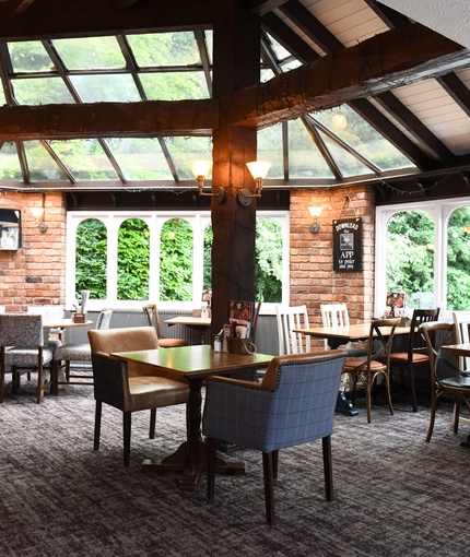 Interior conservatory of a pub with a dining area.
