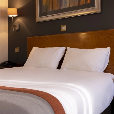 The bed and wooden bedside tables in a hotel room at The Weathervane.