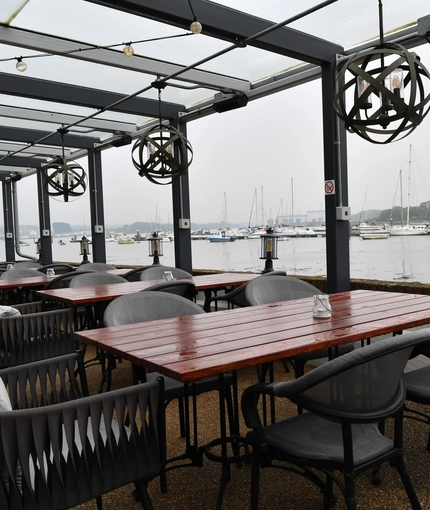 Exterior seating area of a pub next to a body of water.