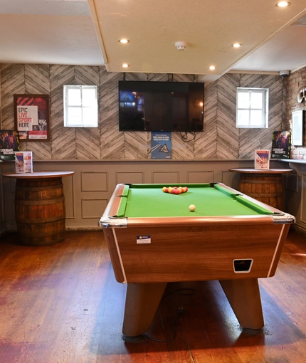 Interior of a pub with a pool table and a TV.