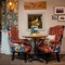 A close up view of one of the small wooden restaurant tables inside The Royal Oak, with two wingback chairs, and framed artwork on the wall.