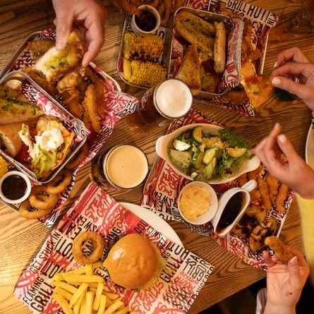 An overhead image showing several mains and sharer dishes sat on a table with a selection of drinks at a Flaming Grill venue.