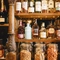 A close up view of bottles of wine, whiskey, and other alcoholic spirits; glass jars filled with nuts and other bar snacks; and glasses, sitting on wooden shelves at the Masons Arms.
