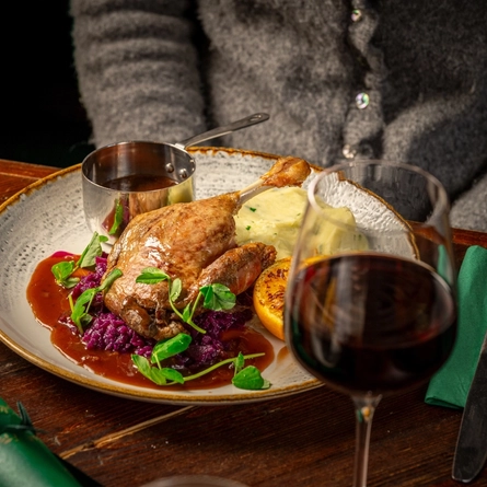 A plated meal on a festive decorated table.  A person whose face is not in teh image is seated at the table.