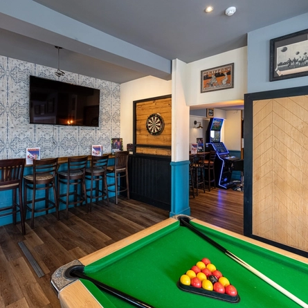 The interior seating and games area with TV, pool table, dartboard and electronic pub games at The Wheatsheaf.