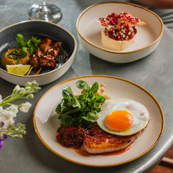 A lifestyle image showing a person sat at a table with 3 different dishes and a glass of wine at a Crafted venue.