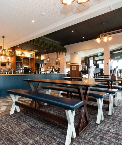 The bar of the Cocked Hat with some bench tables in front of it.