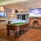 Interior dining area of a pub with a few TVs, a fireplace and a pool table.